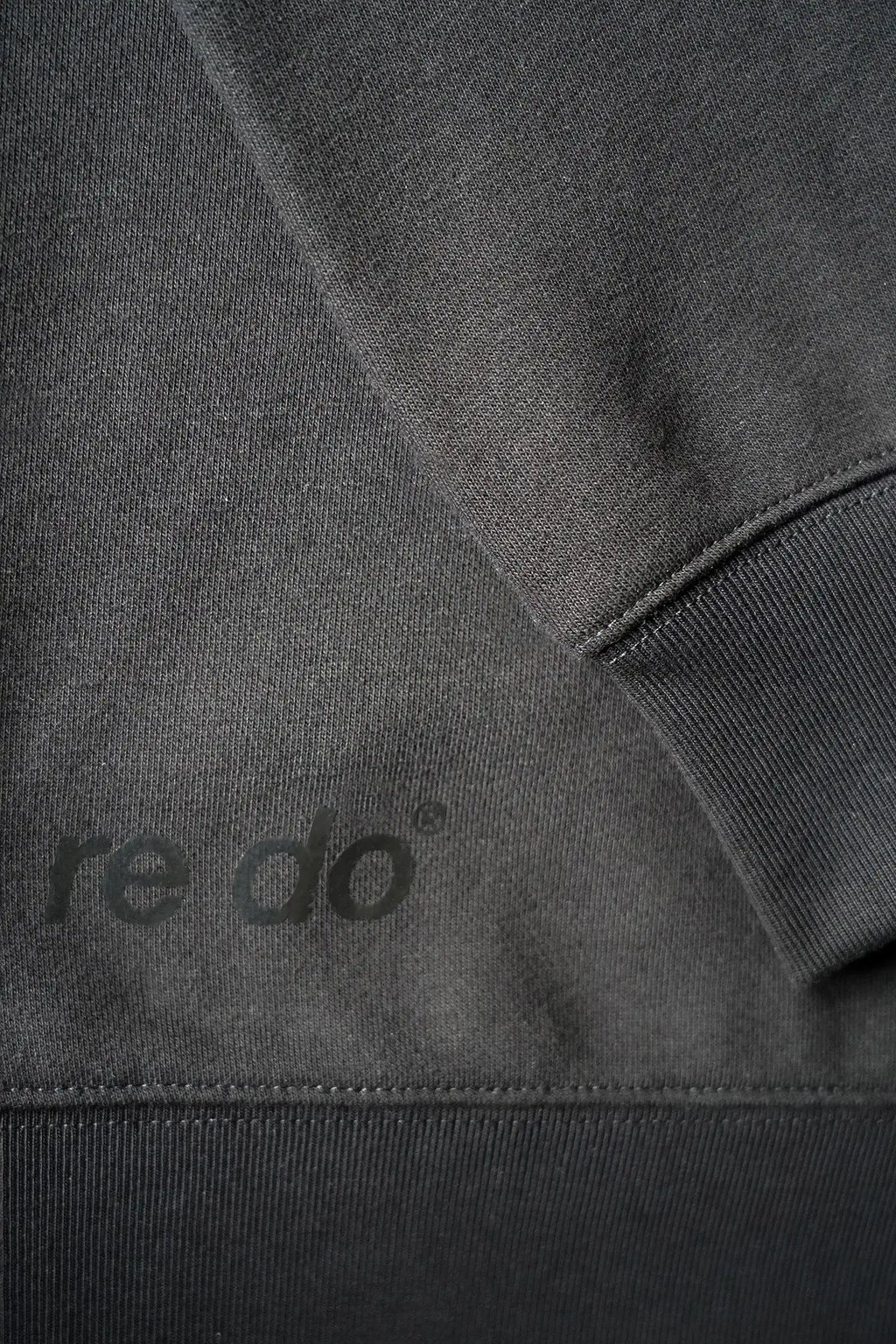 Closeup af ribkant, logo og ærme på re do® Crewneck sweatshirt i sort