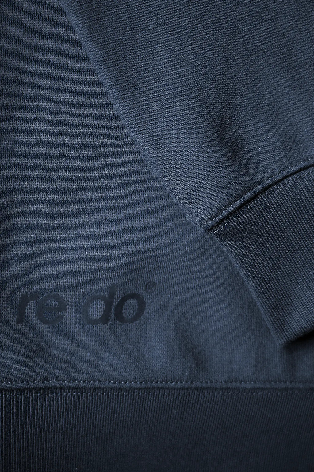 Closeup af ribkant, logo og ærme på re do® Crewneck sweatshirt i Navy Blue