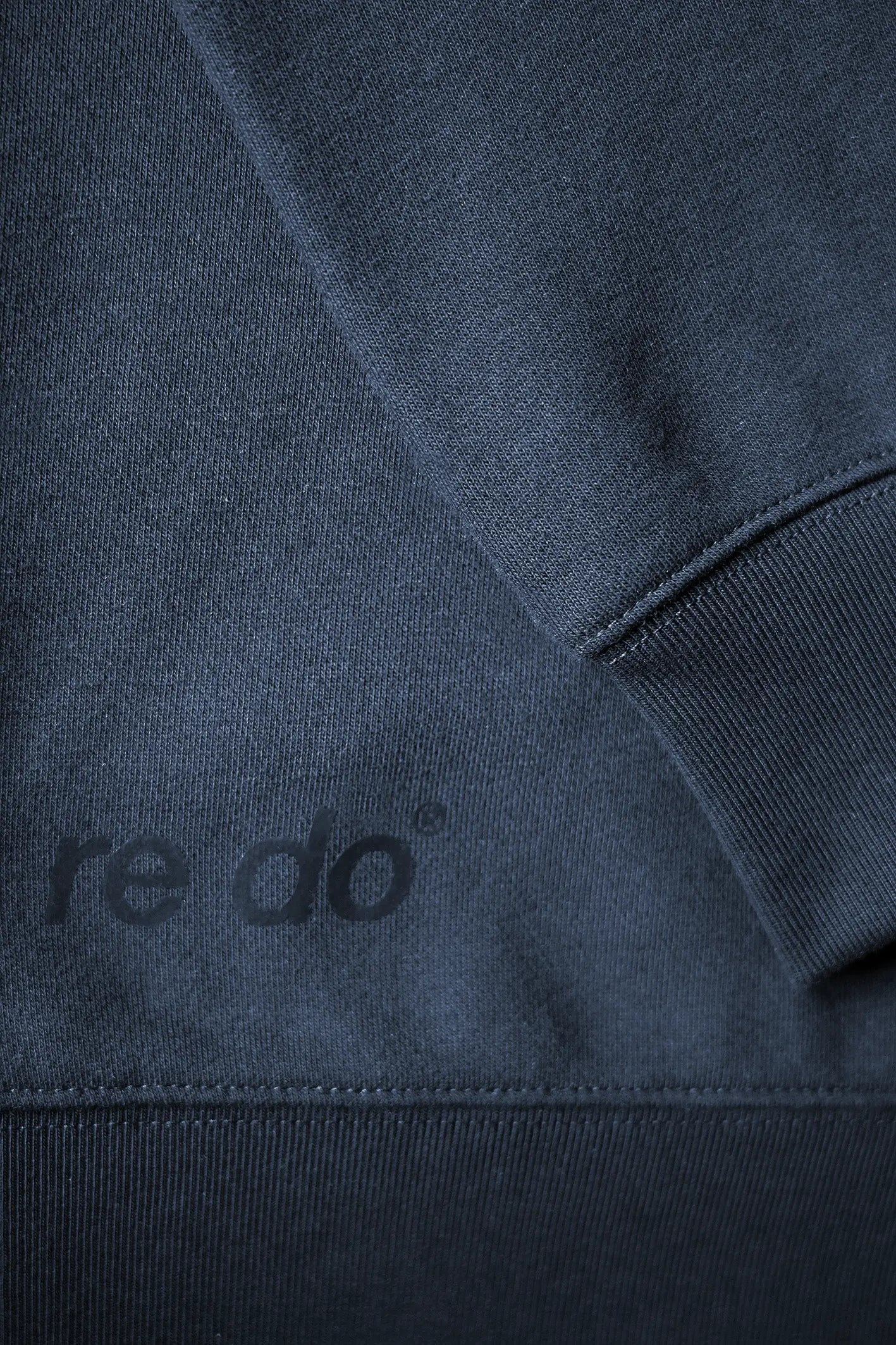 Closeup af ribkant, logo og ærme på re do® Crewneck sweatshirt i Navy Blue