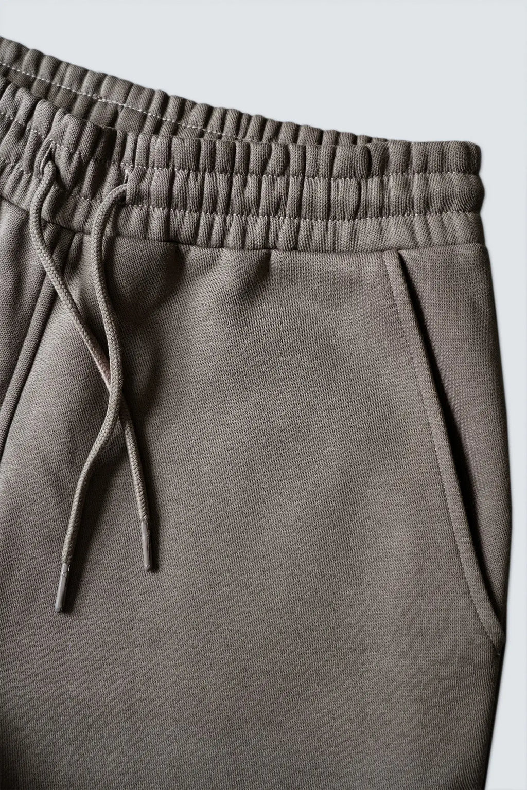 Closeup af elastikkant, bindesnore og sidelomme på re do® sweatpants i Ash Brown