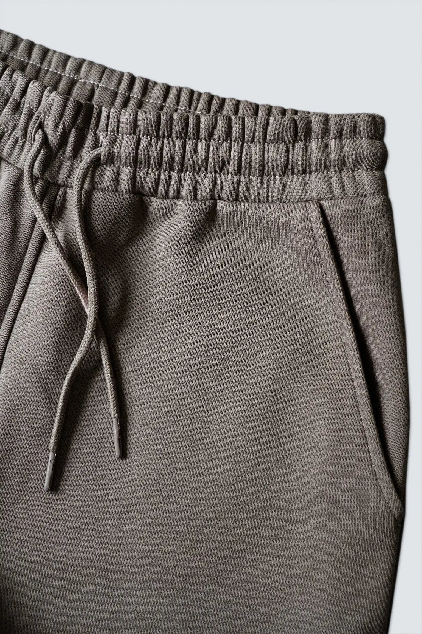 Closeup af elastikkant, bindesnore og sidelomme på re do® sweatpants i Ash Brown