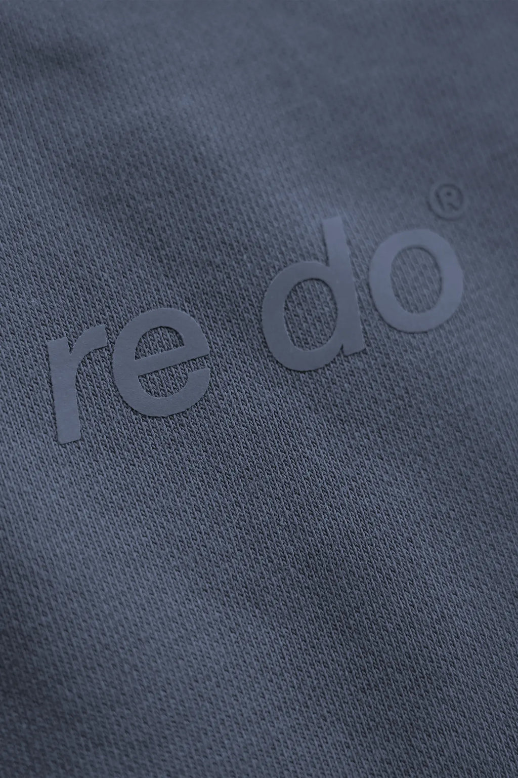 Closeup af logo på re do® sweatpants i #Navy Blue