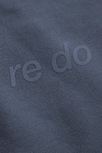 Closeup af logo på re do® sweatpants i #Navy Blue