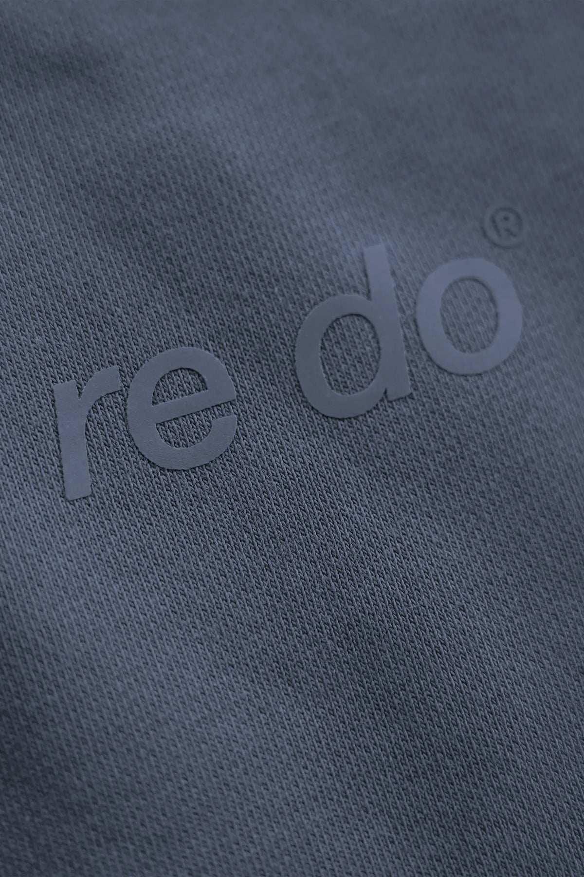 Closeup af logo på re do® sweatpants i #Navy Blue