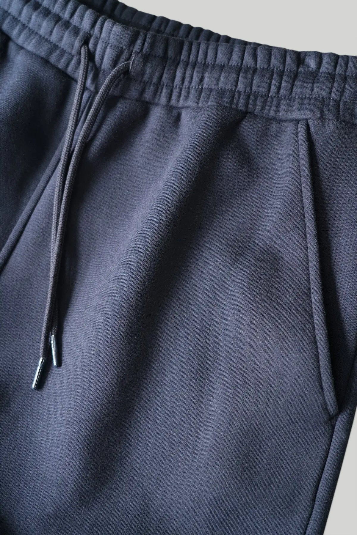 Closeup af elastikkant, bindesnore og sidelomme på re do® sweatpants i #Navy Blue