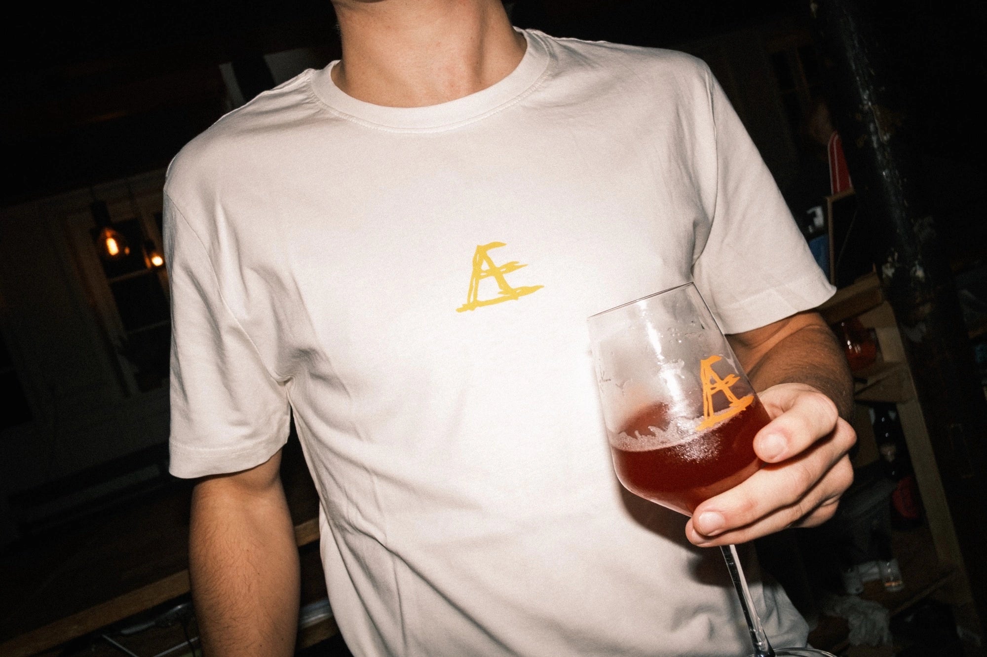 T-shirt med tryk fra re do® i Star White, model Frej i bomuld, præsenteret i collab med Café Mundhæld i afslappet barsituation.