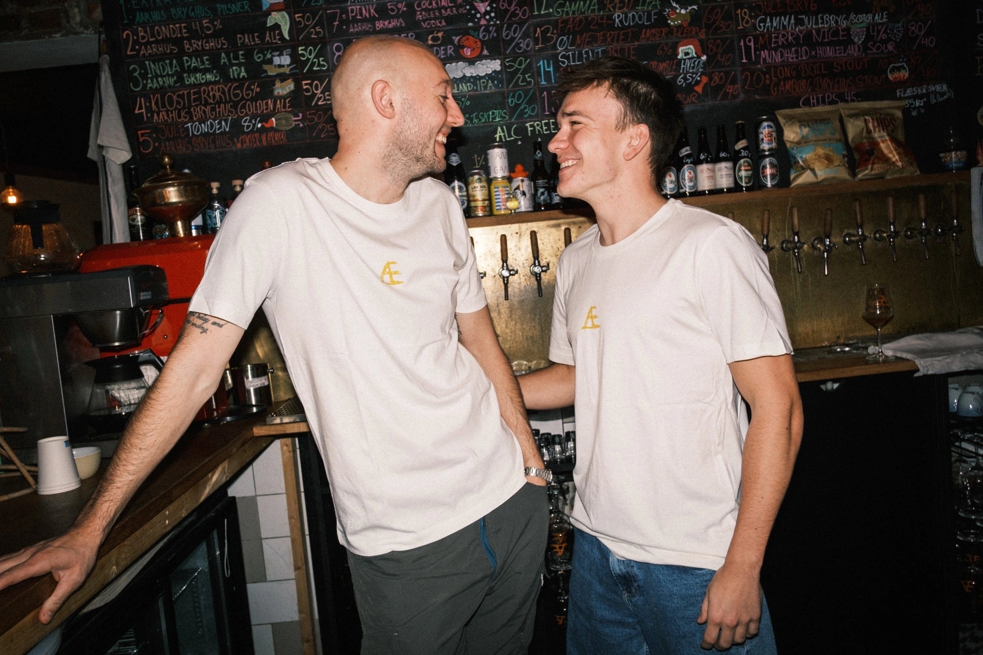 To medarbejdere iført T-shirt med tryk fra re do® i Star White, model Frej i bomuld, i collab med Café Mundhæld.