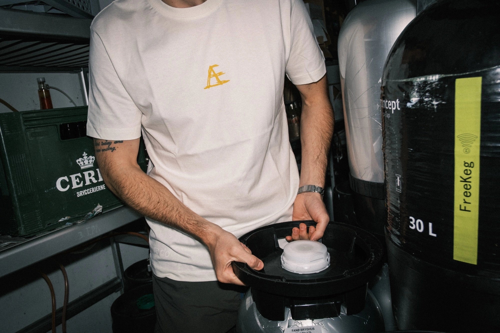 T-shirt med tryk fra re do® i farven Star White, model Frej i bomuld, vist i collab med Café Mundhæld i autentisk arbejdssituation bag baren.