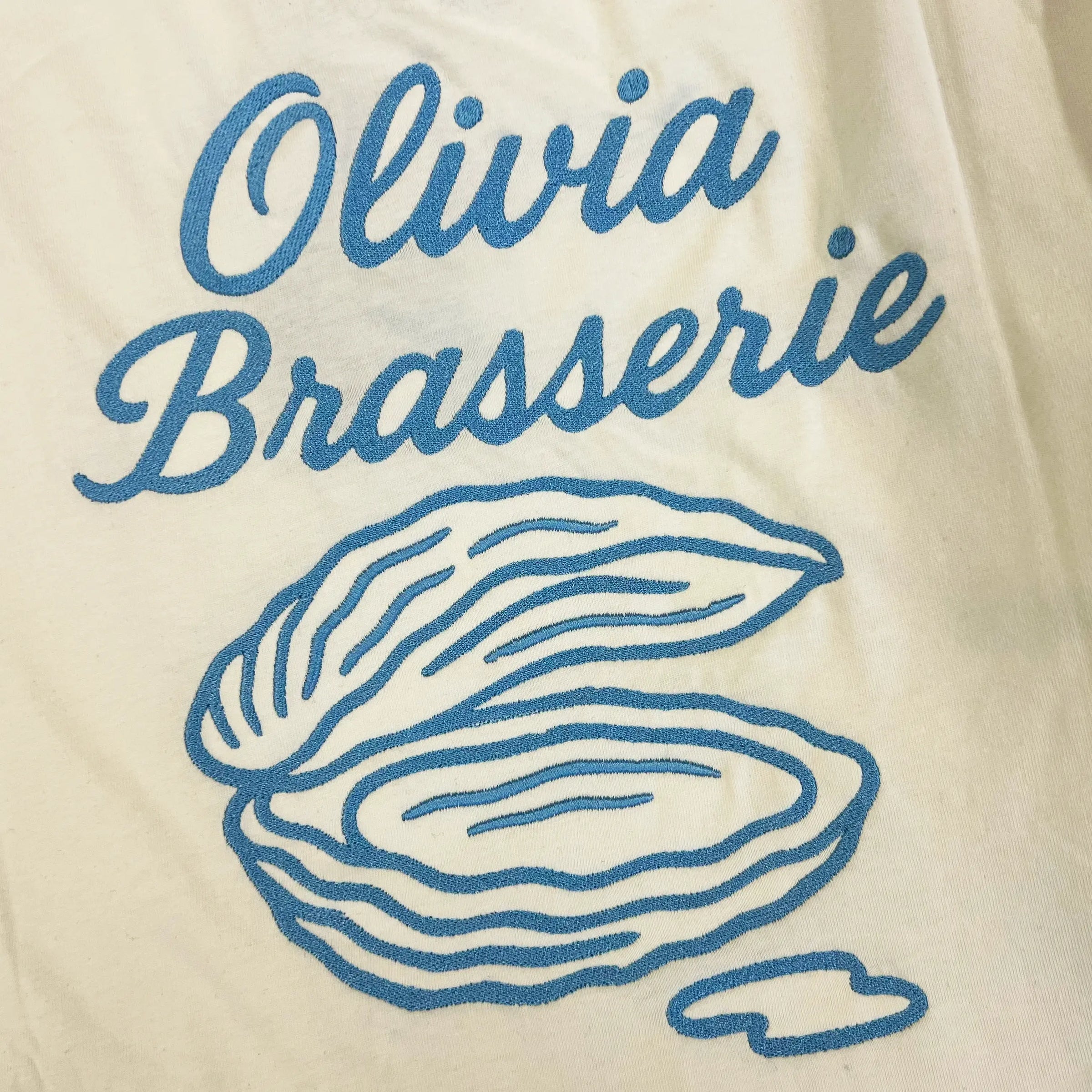 Bomuld T-shirt i Star White fra re do® med broderi fra BrandLabs, collab med Olivia Brasserie. Firmatøj med logo. 