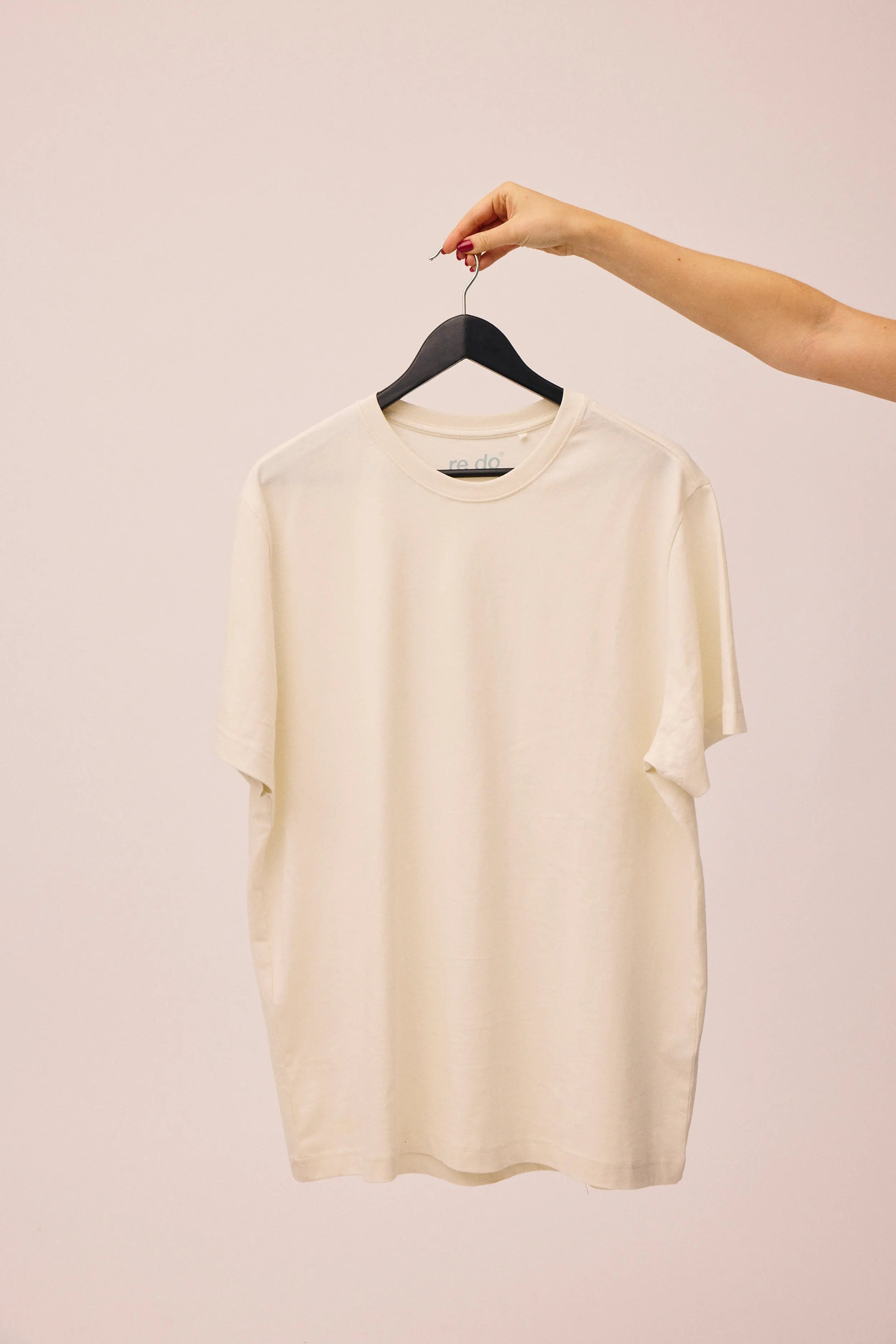 Hånd der holder bomuld t-shirt i Star White fra re do®