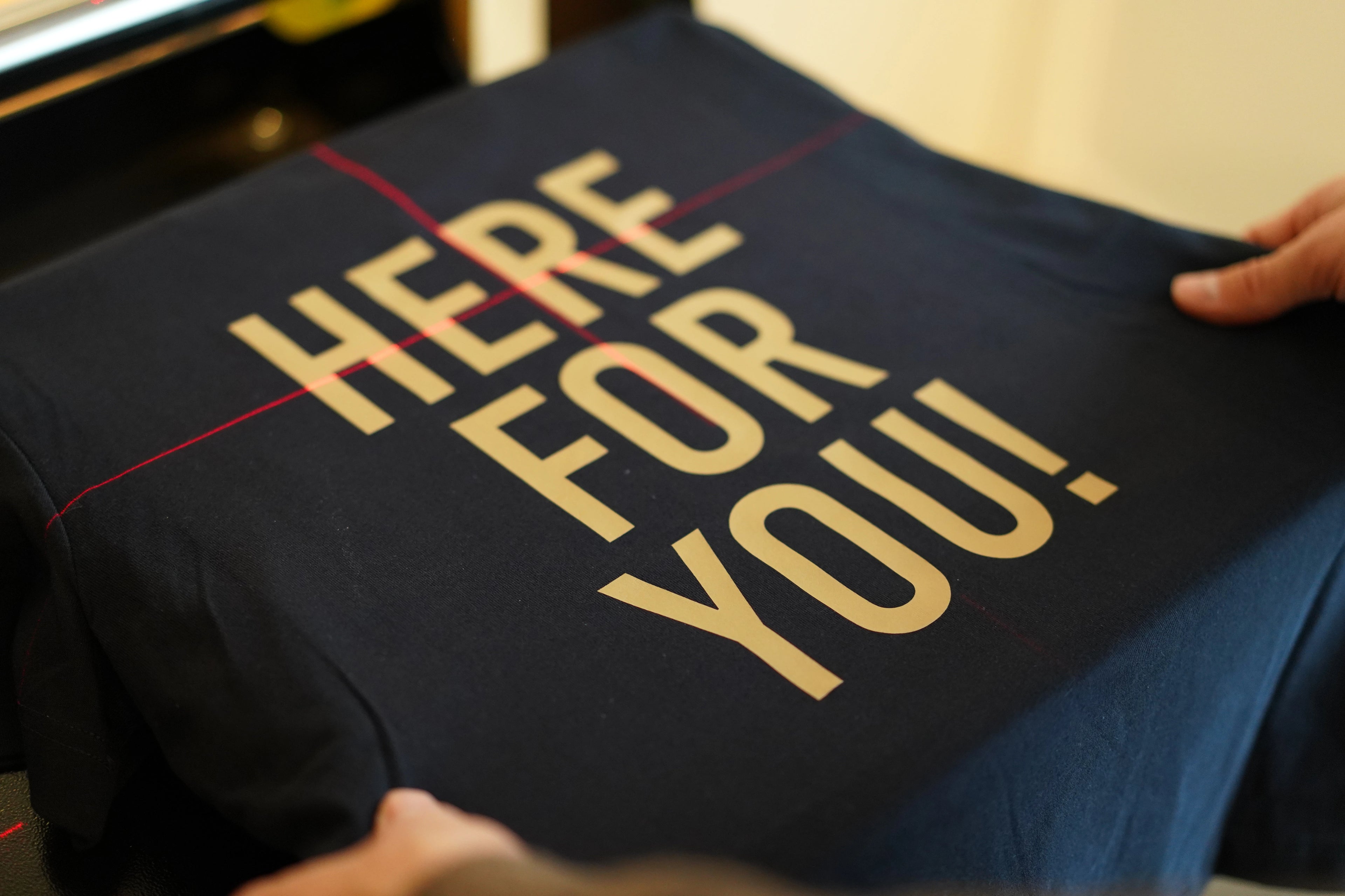 re do® tøj med logo, firmatøj med tryk. re dos trykproces – trykt logo i gul på blå t-shirt med glat overflade.