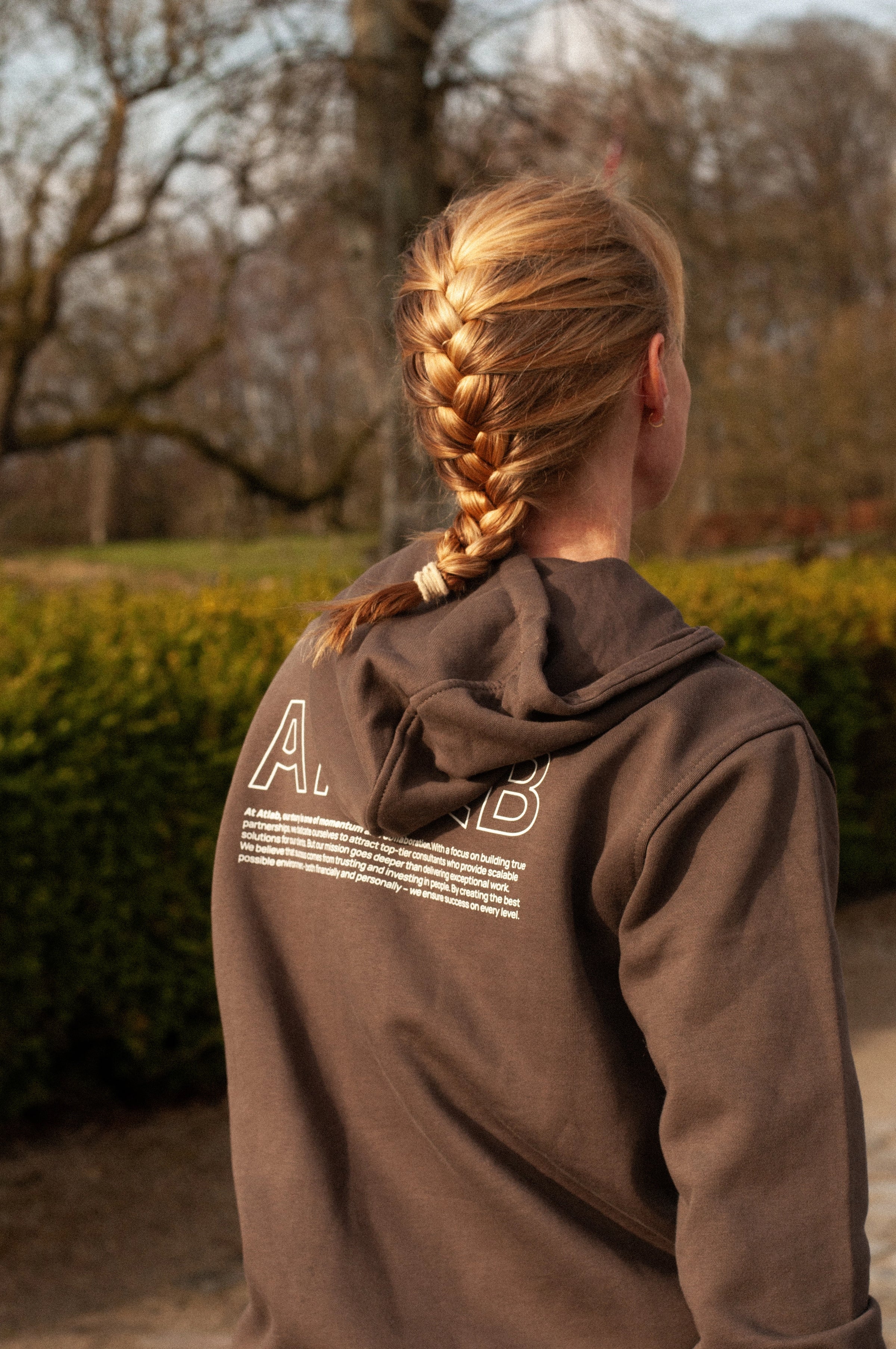 re do x Atlab collab. Person set bagfra i hoodie som firmatøj med tryk fra re do® og tøj med logo fra re do® i naturen.